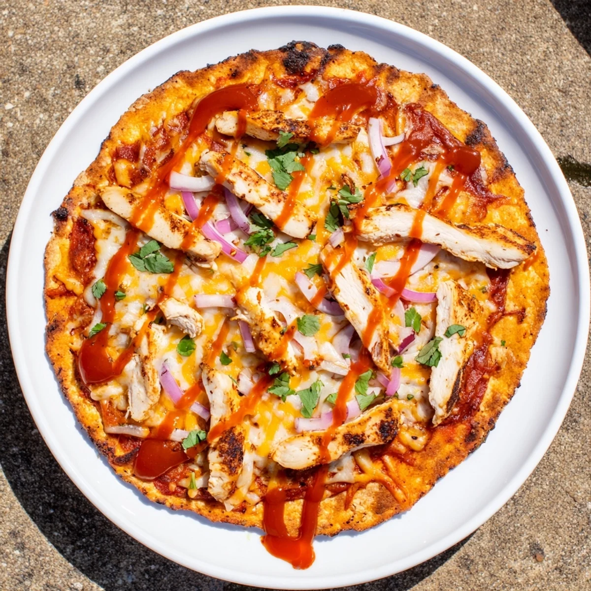 Golden grilled BBQ chicken pizza with melted cheese, red onion, and fresh cilantro on a charred crust