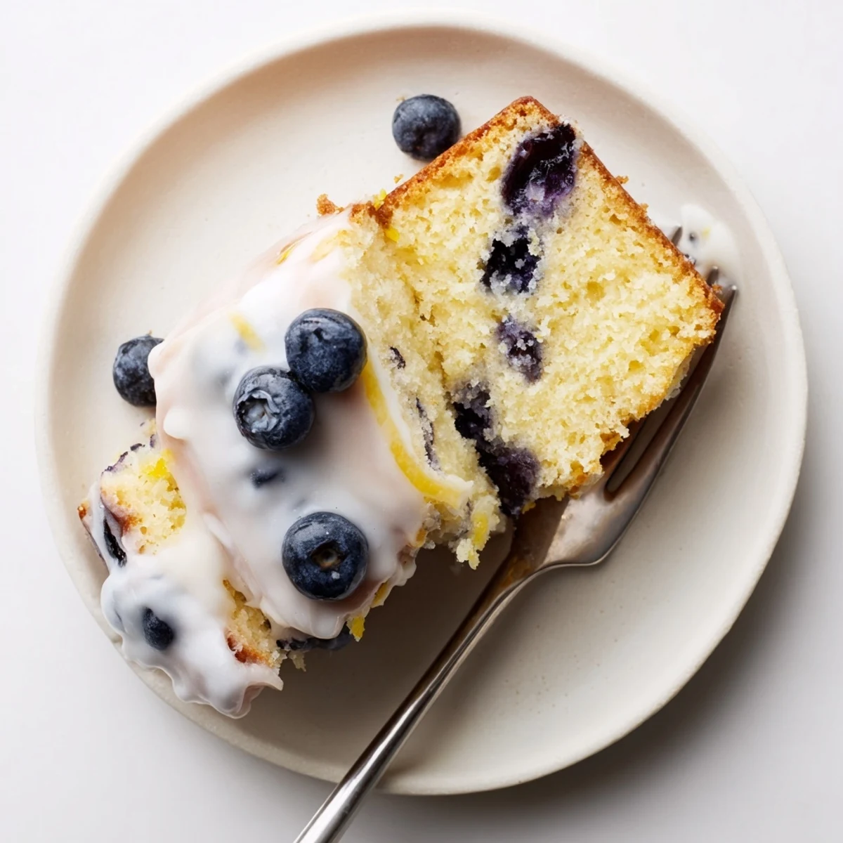 Moist lemon blueberry cake slice revealing purple fruit pockets inside a tender yellow crumb
