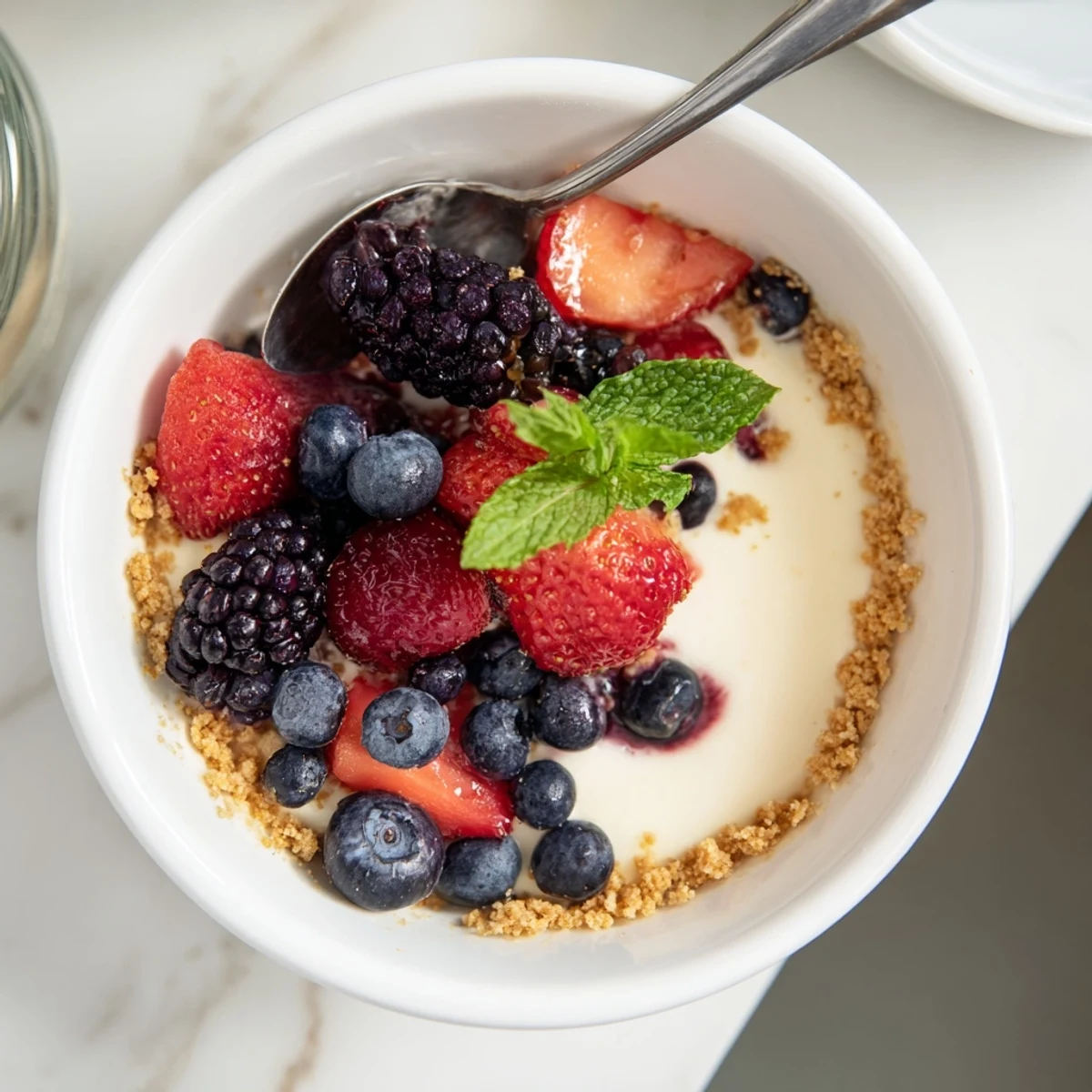 Summer dessert bowl showing no bake berry cheesecake bowls with mint garnish and juicy berry topping
