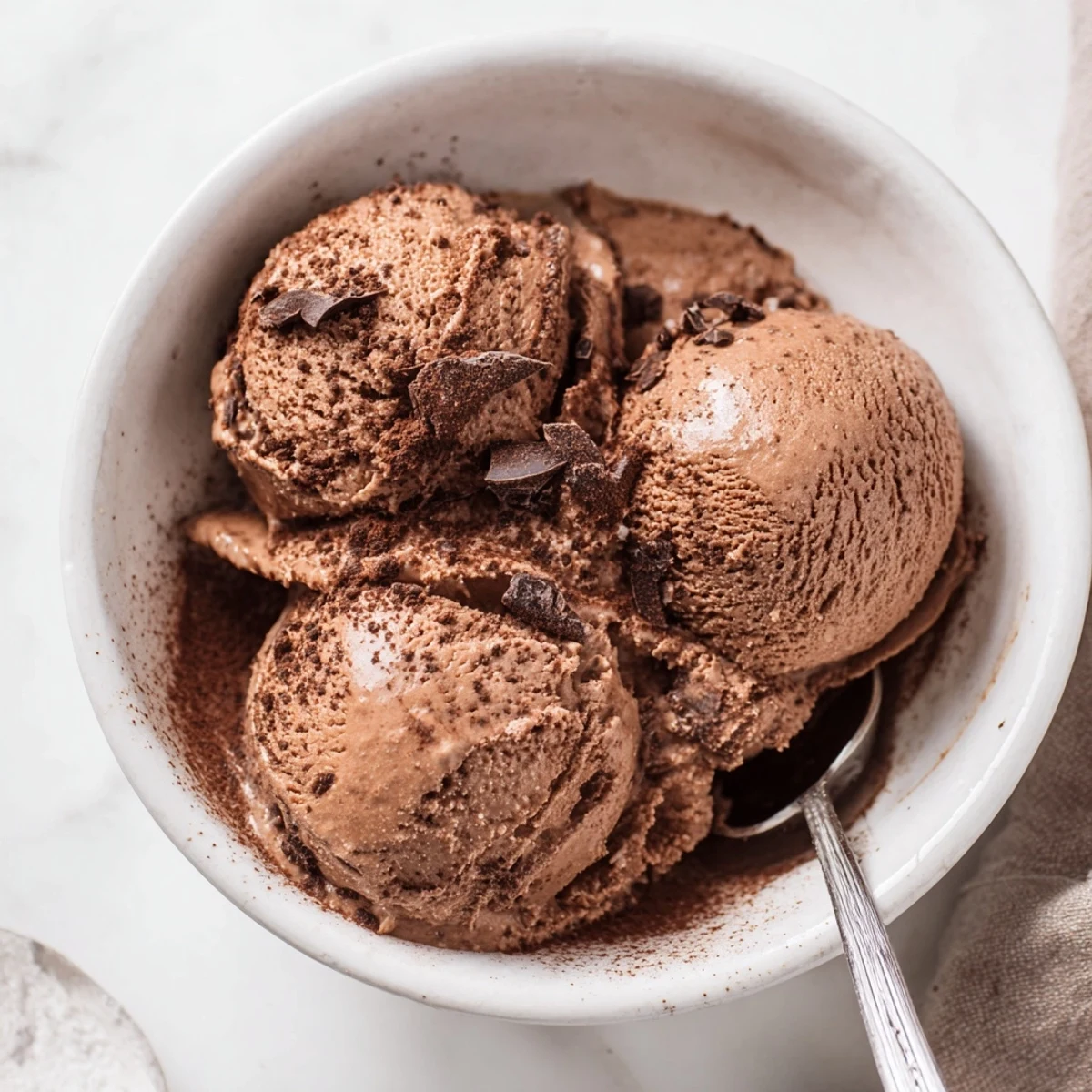 Creamy chocolate sourdough ice cream scooped into a bowl topped with fresh raspberries and sea salt