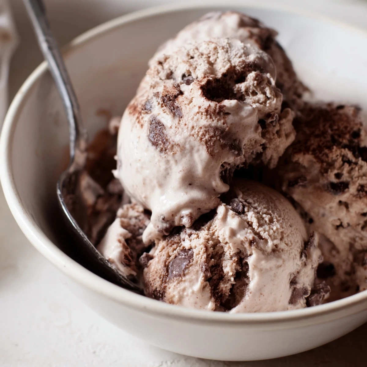 Rich chocolate sourdough ice cream sits in a chilled waffle cone with chocolate drizzle