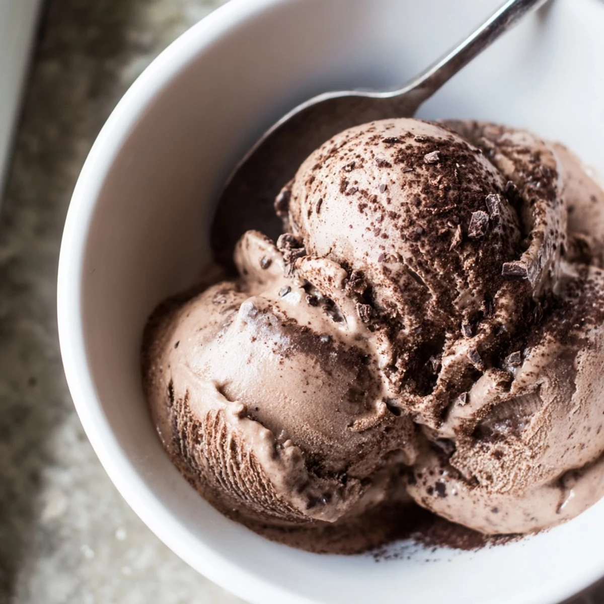 Dark chocolate sourdough ice cream swirls in a vintage glass dish garnished with mint sprigs