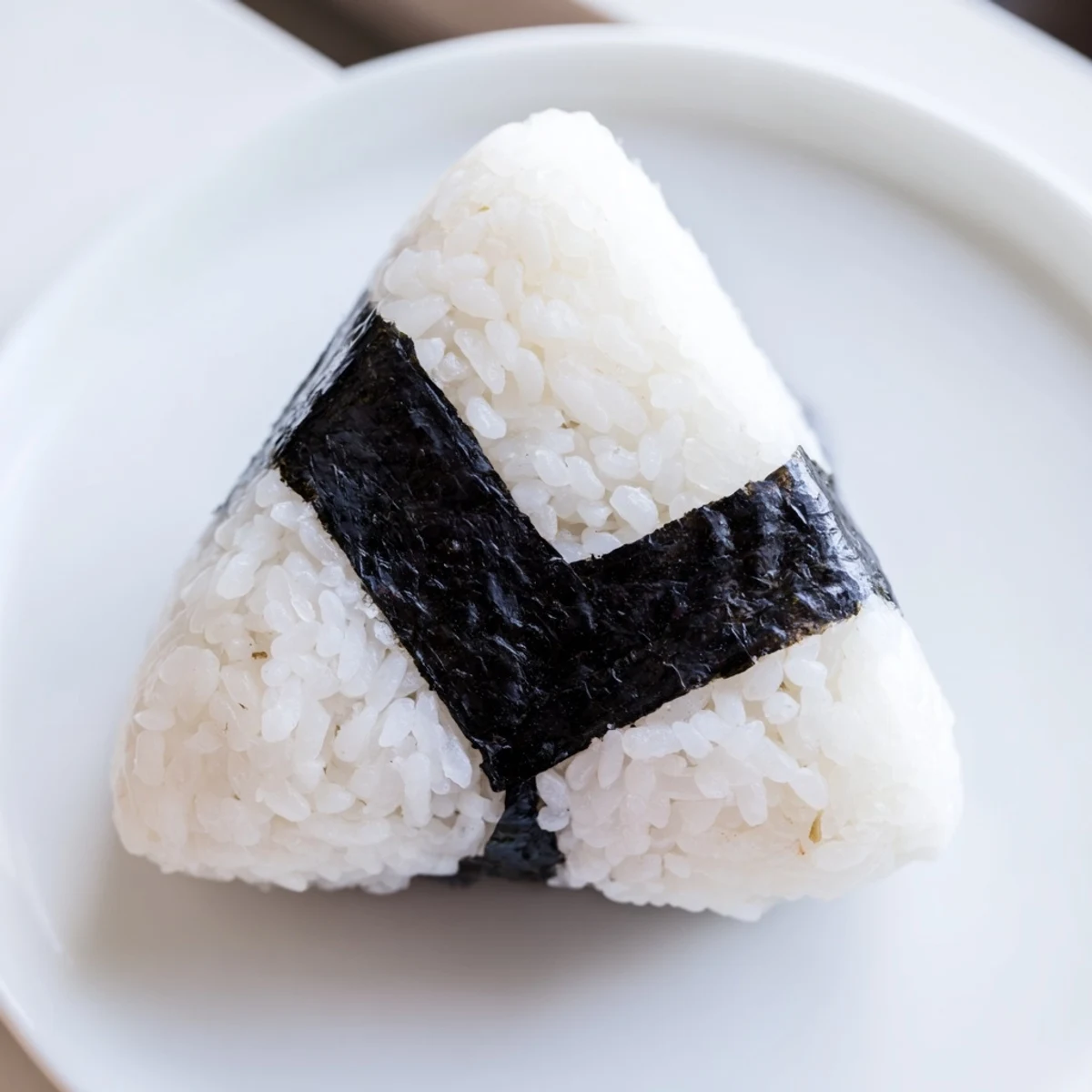 Steaming warm tuna mayo onigiri arranged on white plate, perfect for portable lunch or snack