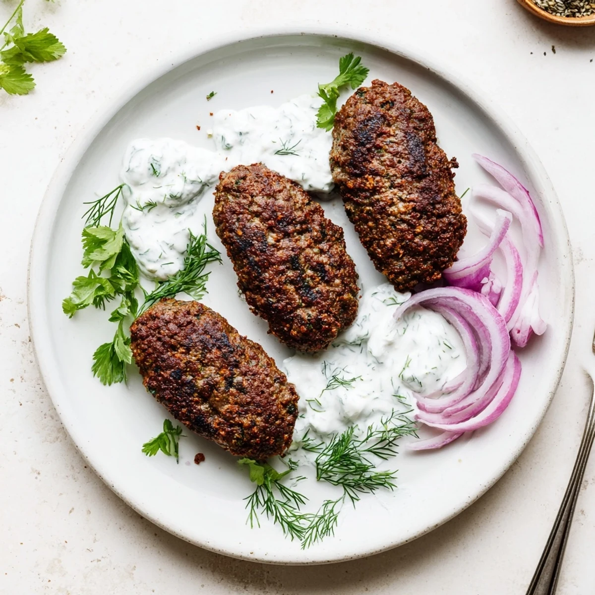 Juicy hand-shaped beef kebabs with smoky char edges topped with tangy cucumber yogurt dollops
