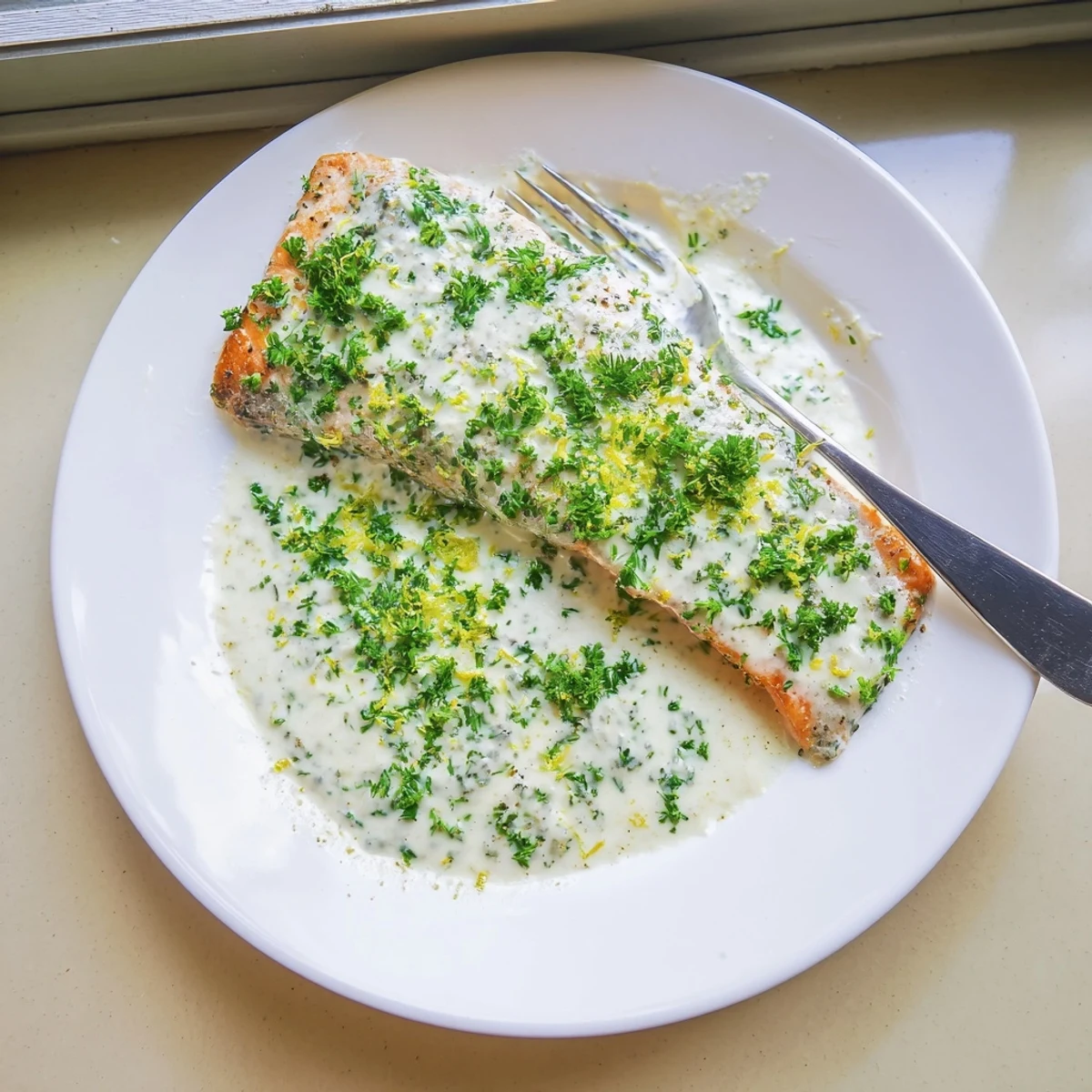 Flaky salmon with lemon cream sauce served on a white plate with garnish
