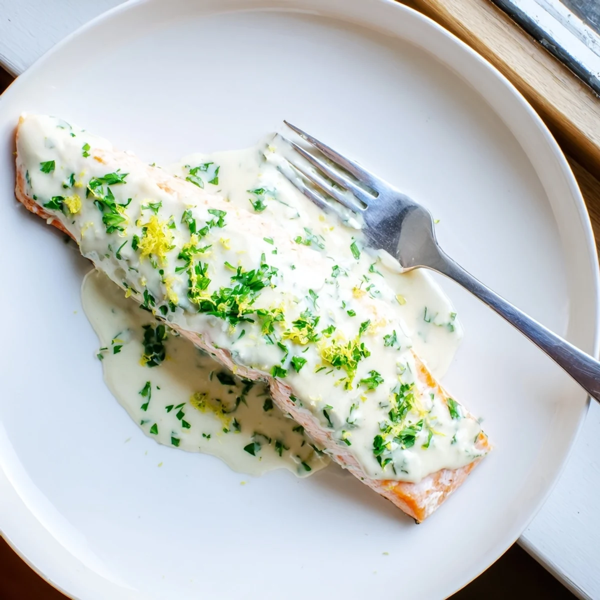 Succulent salmon fillets topped with zesty lemon cream sauce and chopped herbs
