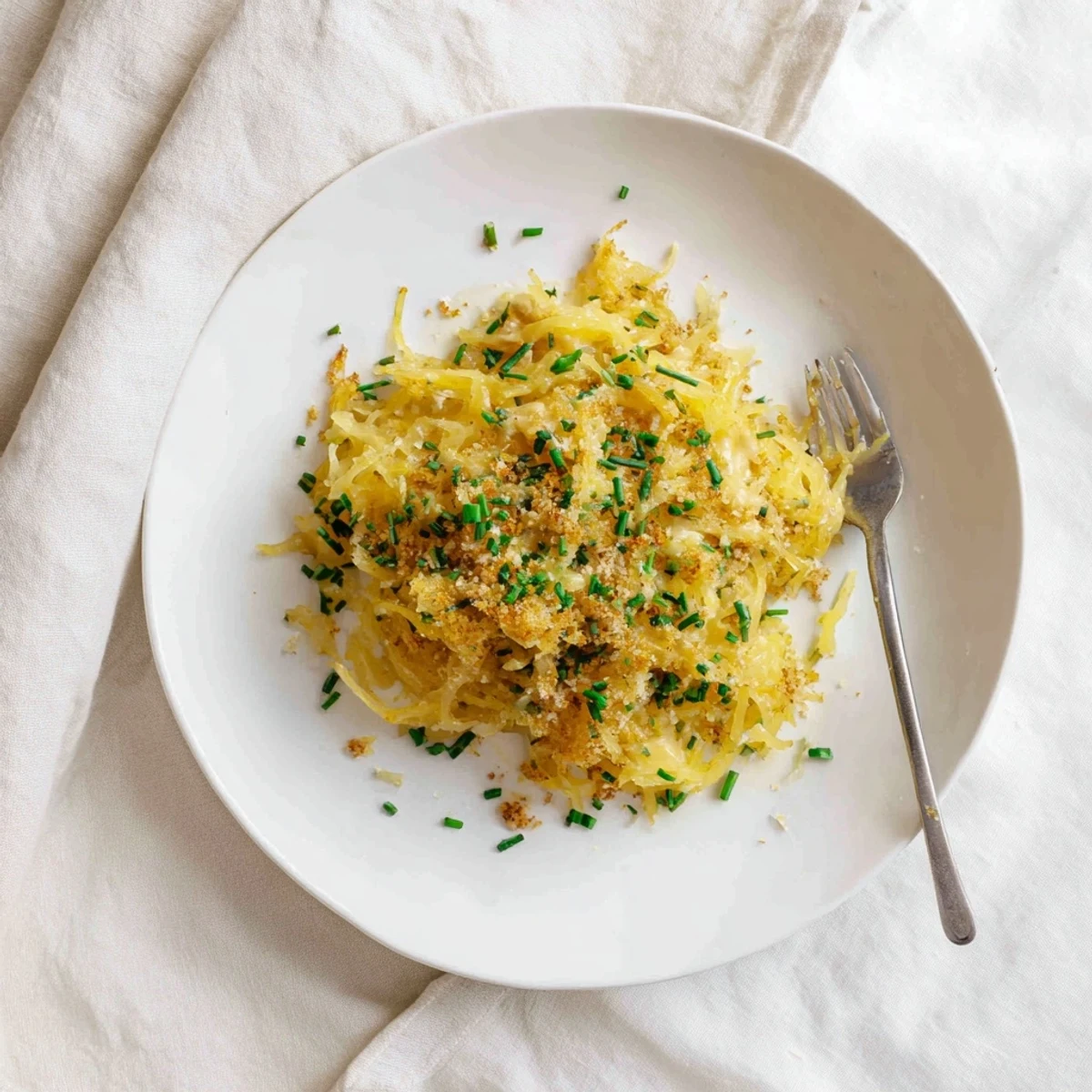 Golden bowl of spaghetti squash mac cheese topped with crispy breadcrumbs and fresh chives