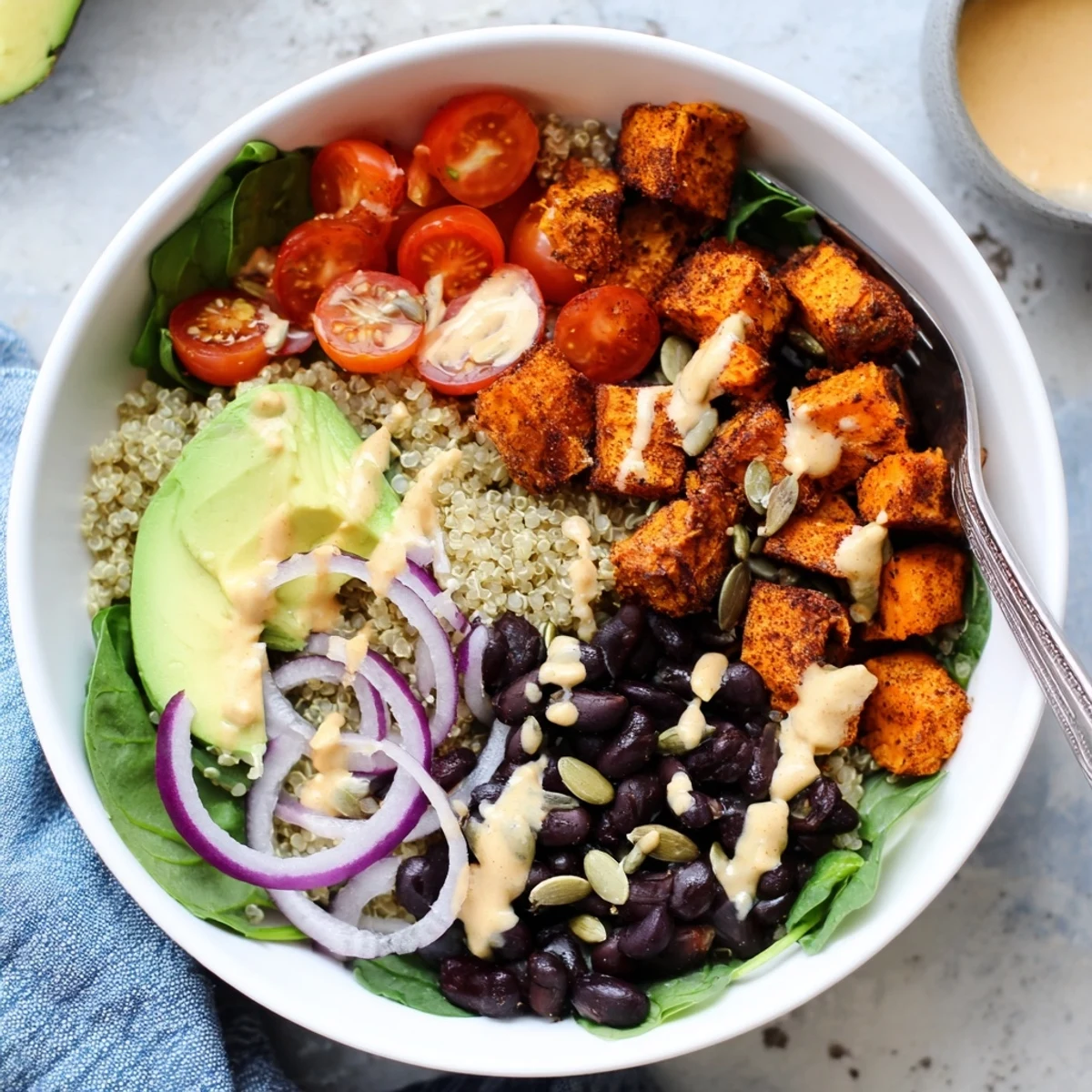 Sweet potato bowl loaded with avocado black beans quinoa and caramelized vegetables