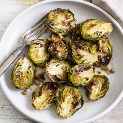Halved Brussels sprouts roasted alongside smoky chopped turkey bacon, showing caramelized edges on a parchment-lined baking sheet.