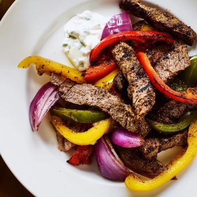 A close-up of Sheet Pan Steak Fajitas with colorful vegetables and warm flour tortillas ready for dinner.
