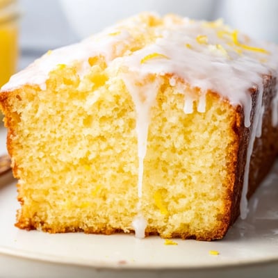 Slices of moist Lemon Bread Loaf served beside steaming tea on a cozy breakfast table.