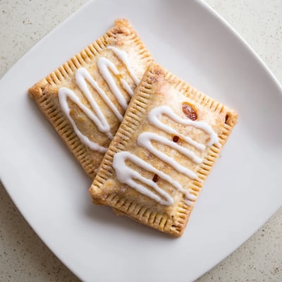 A close-up shows Protein Pop Tarts drizzled with icing, served on a rustic wooden table.
