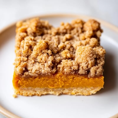 Creamy pumpkin maple filling peeks through a crumbly brown sugar crust on these autumn dessert bars